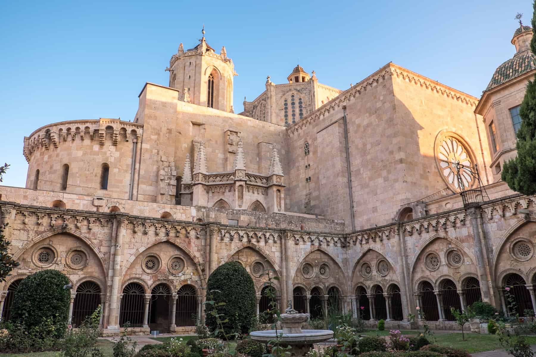 The golden stone, glowing in sunlight, of the Tarragona Cathedral Spain. This is the exterior of the structure from the view of the gardens. 