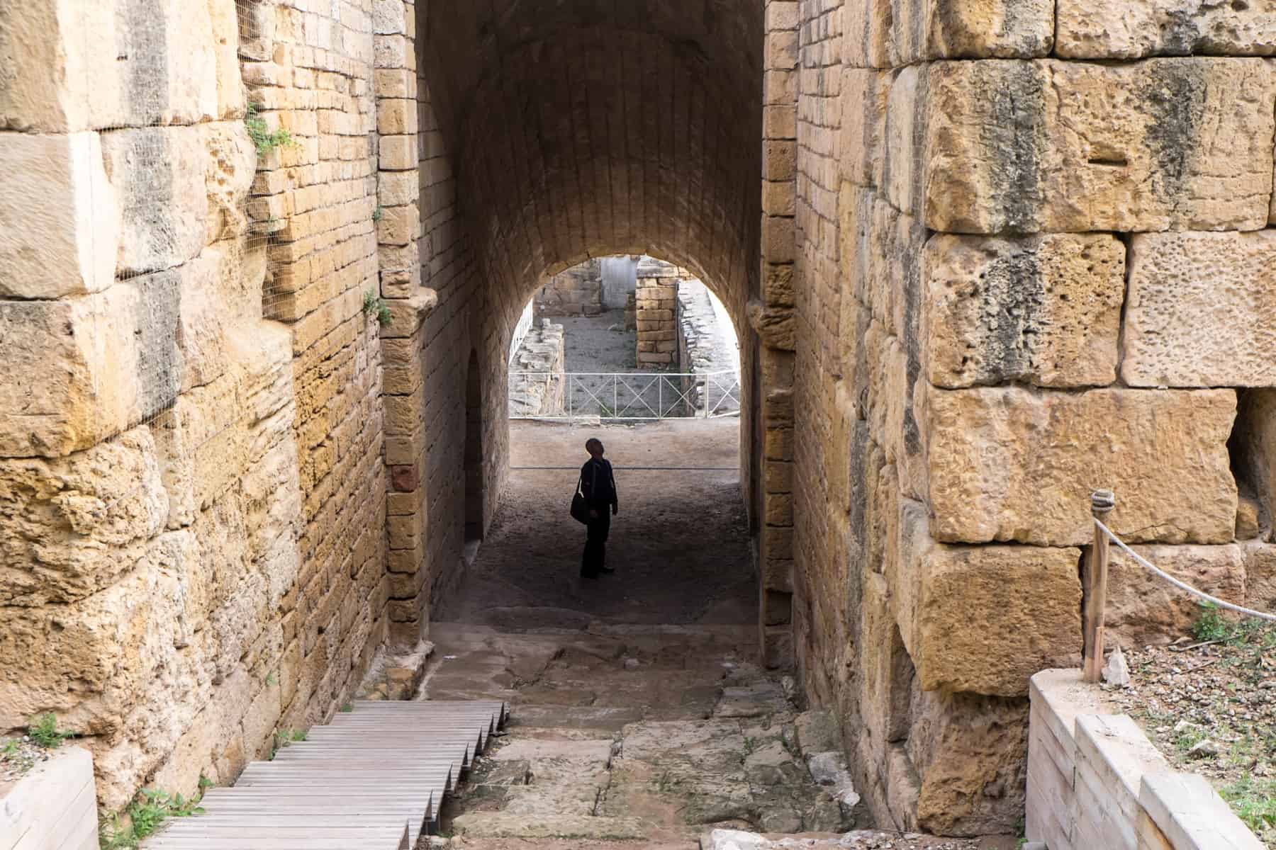 A man stands in the high stone doorway entrance of the yellowing stoned Roman Tarragona Amphitheatre in Spain
