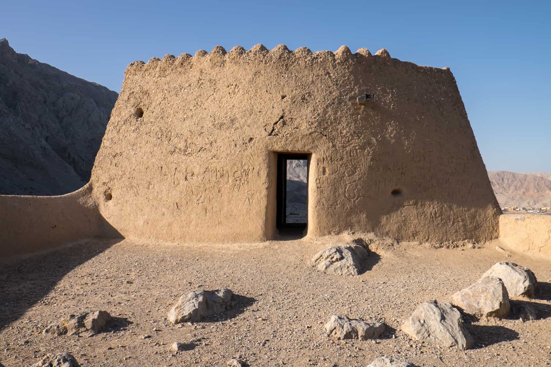 The golden castle-like structure of Dhayah Fort in Ras Al Khaimah, that sits elevated on dusty grounds and surrounded by mountains.