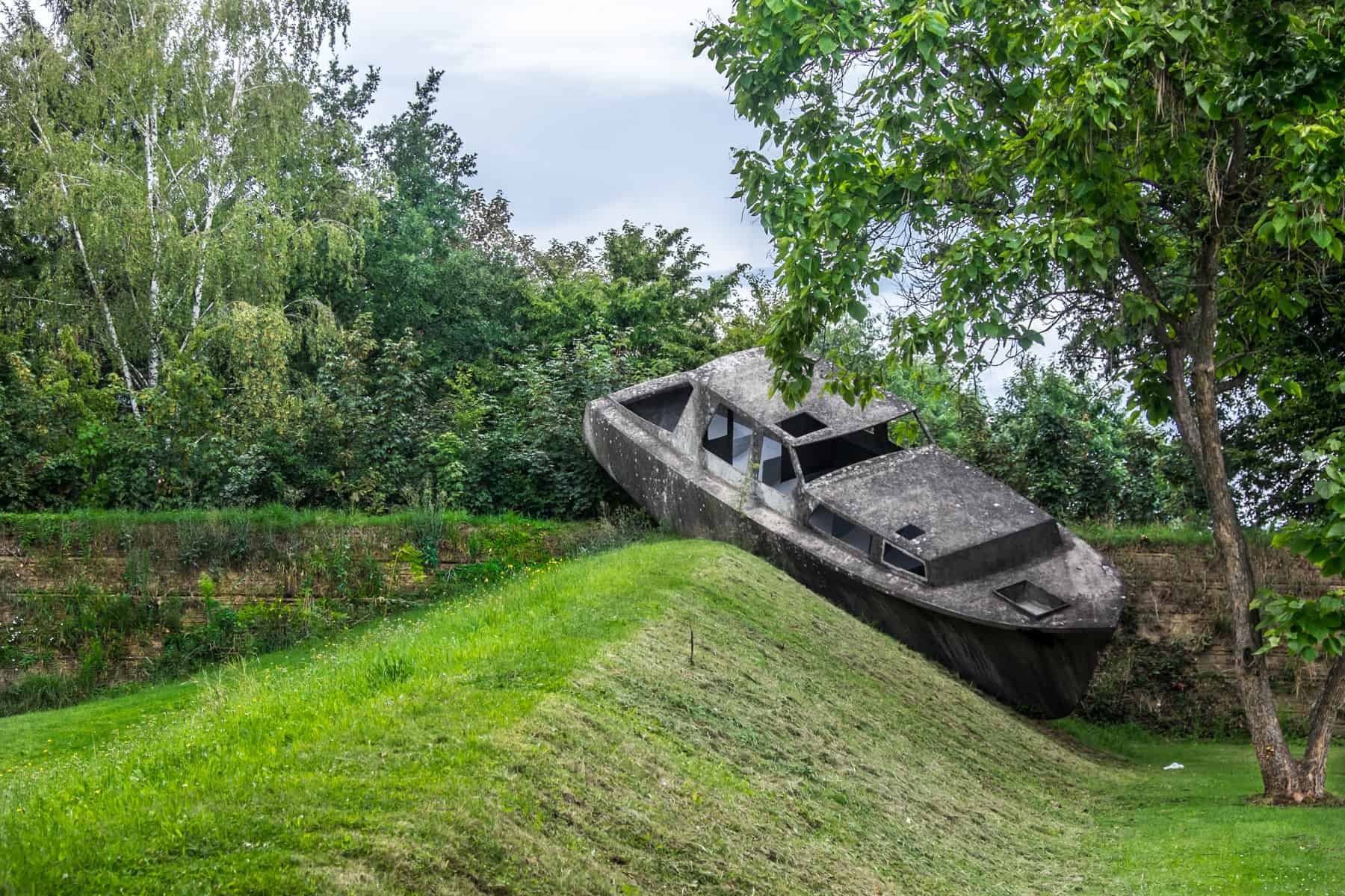 A concrete boat rests at an angle on sloping grass - one of the artworks at the ustrian Sculpture Park near Graz