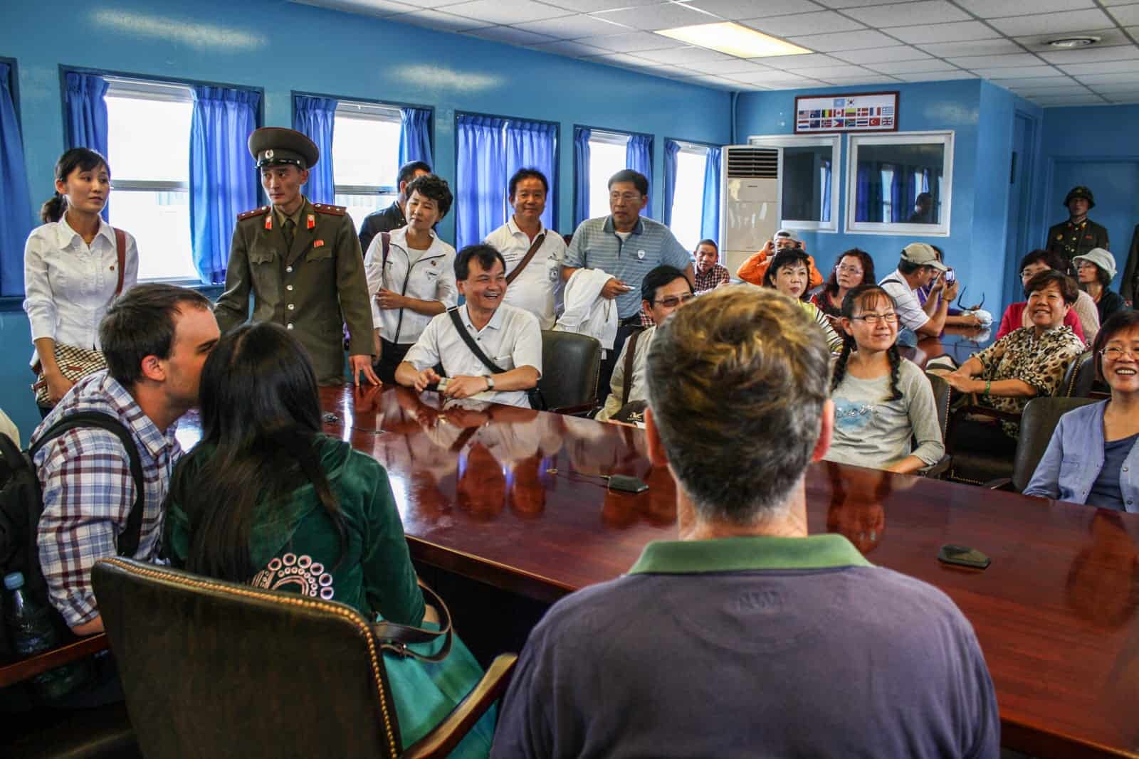 Tourists sit around the table in the Military Armistice Commission Conference Room when visiting the DMZ in North Korea 