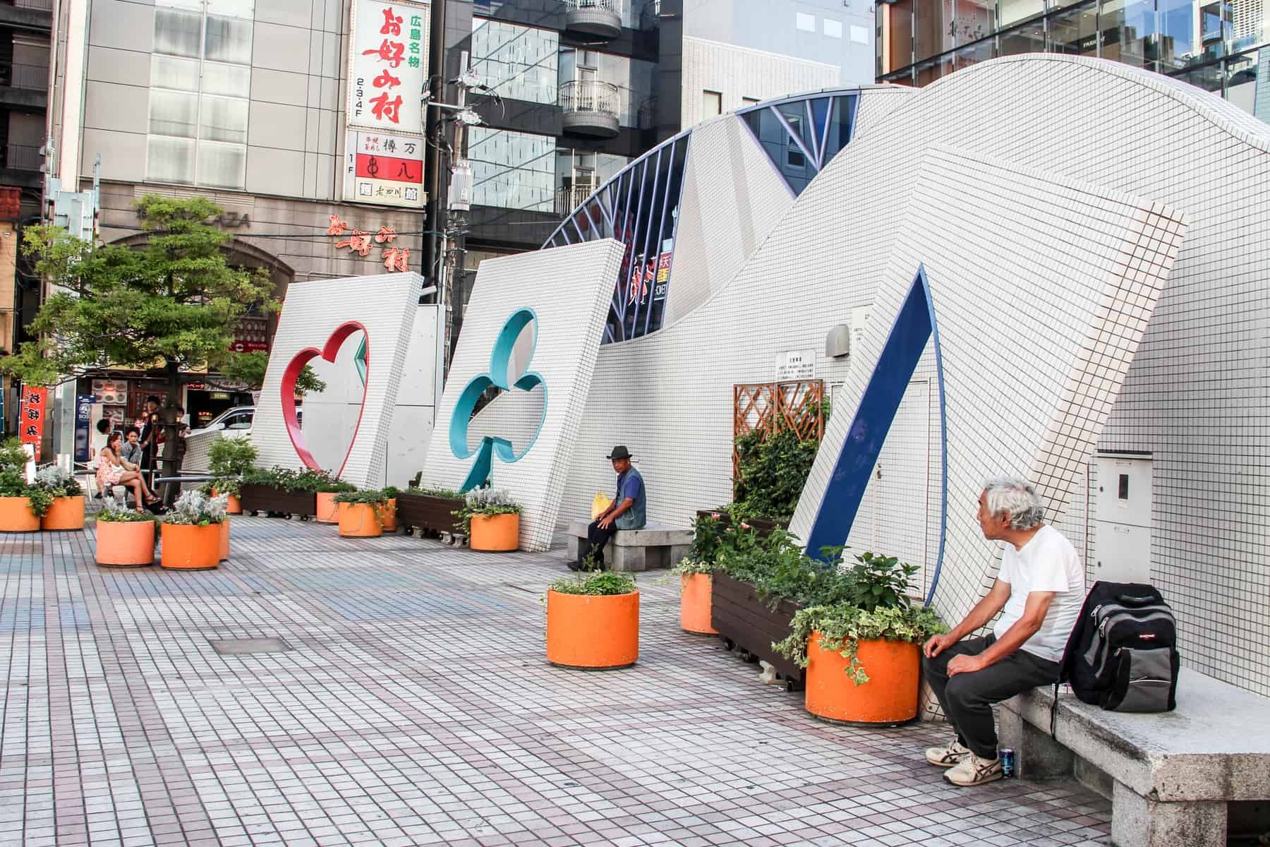 Two men sit on the benches of a playing card themed sculpture in Hiroshima city, Japan. 