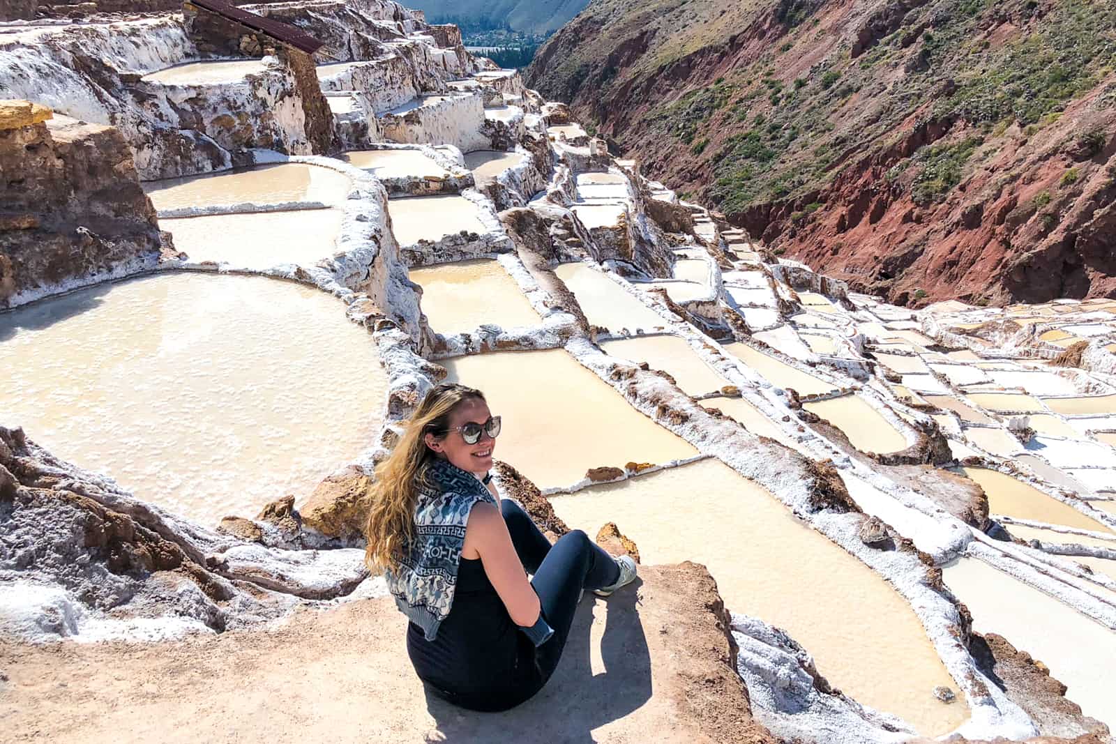 Woman sitting at Salinas salt ponds in Cusco, Peru and the sacred valley.