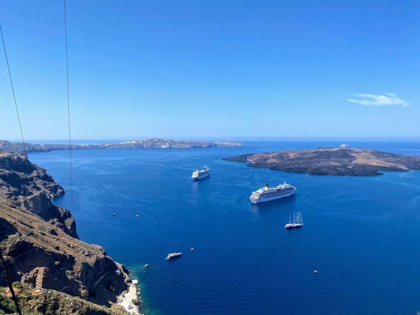 Size of Running on Waves yacht versus large cruise ships docked in Santorini. Panorama from the cable car up to Fira.