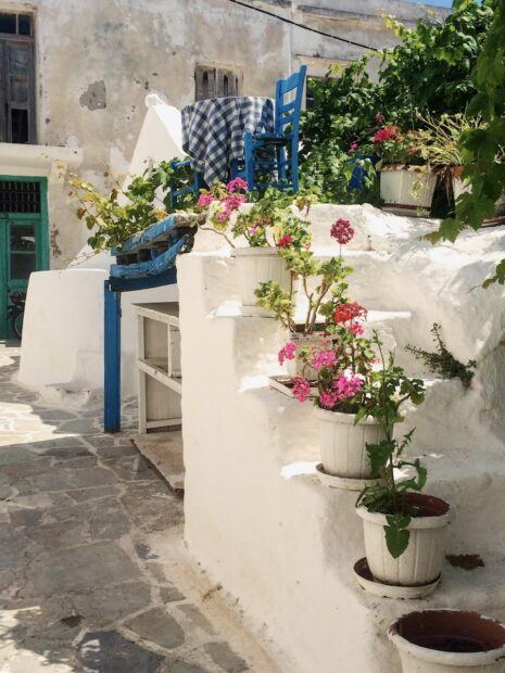 White steps with pink plants and blue table and chairs in Naxos
