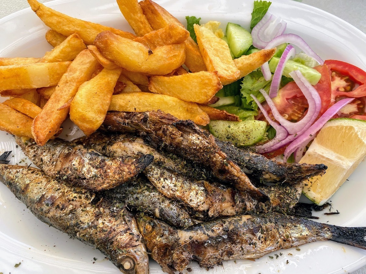 Grilled sardines served with chips and salad