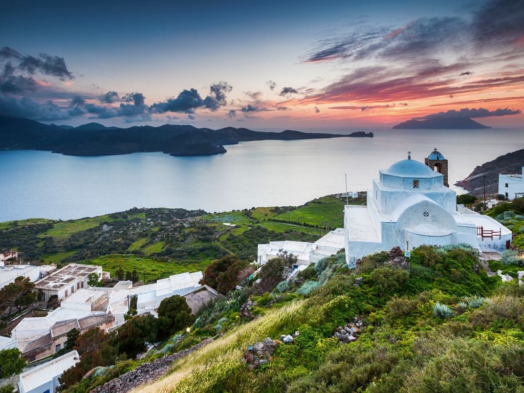 White and blue domed church in milos with sea views