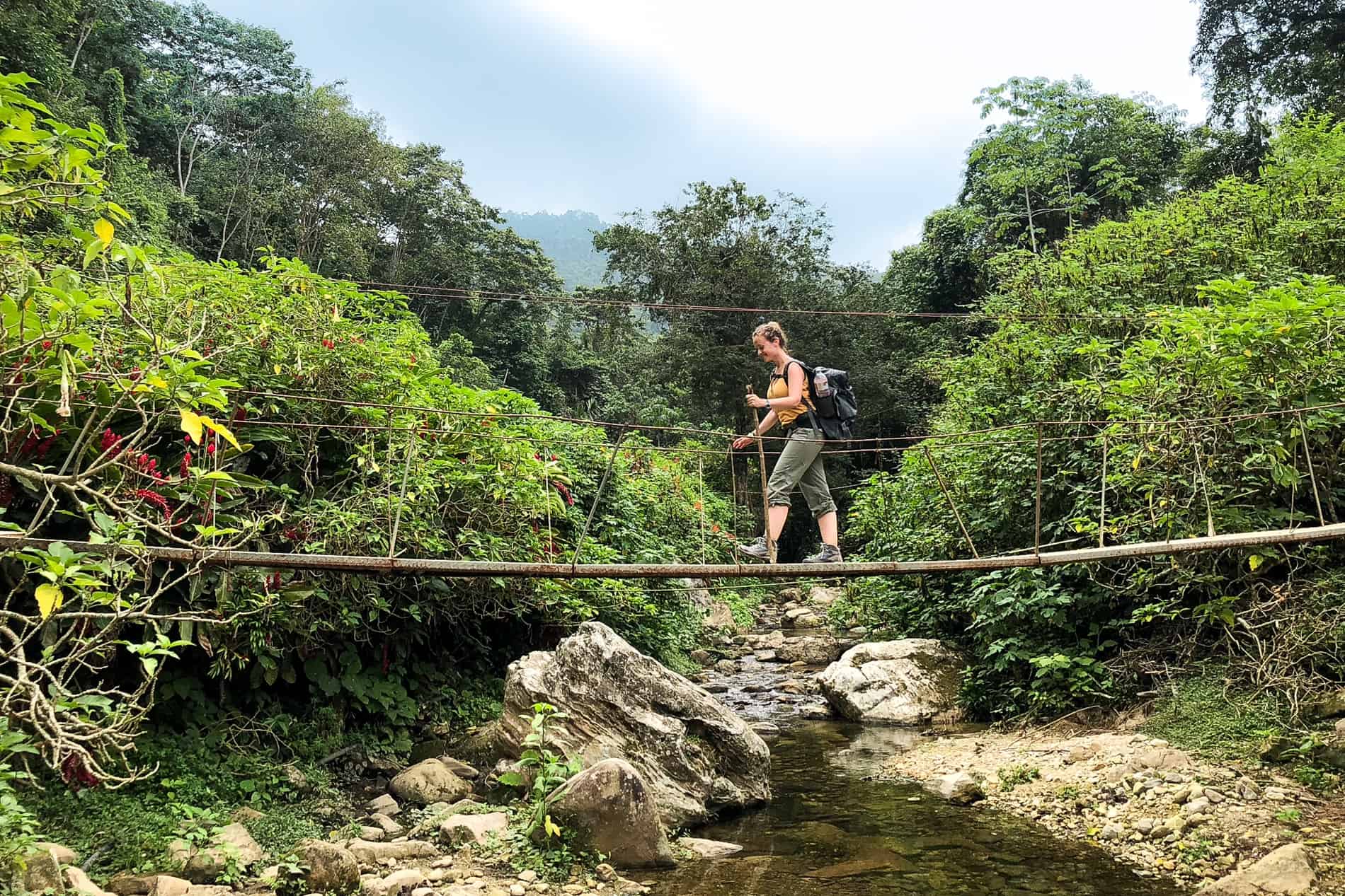 A trekker crossing a river bridge in the jungle on the way to the Lost City.