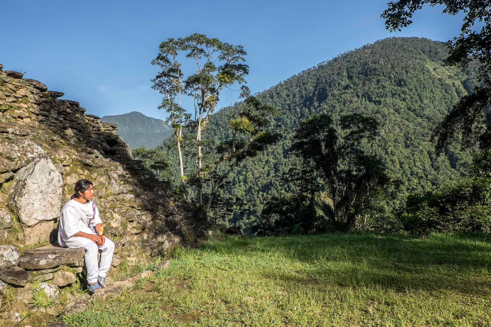 Wiwa indigenous guide sits on the stone ruins of the Lost City Ciudad Perdida in Colombia.