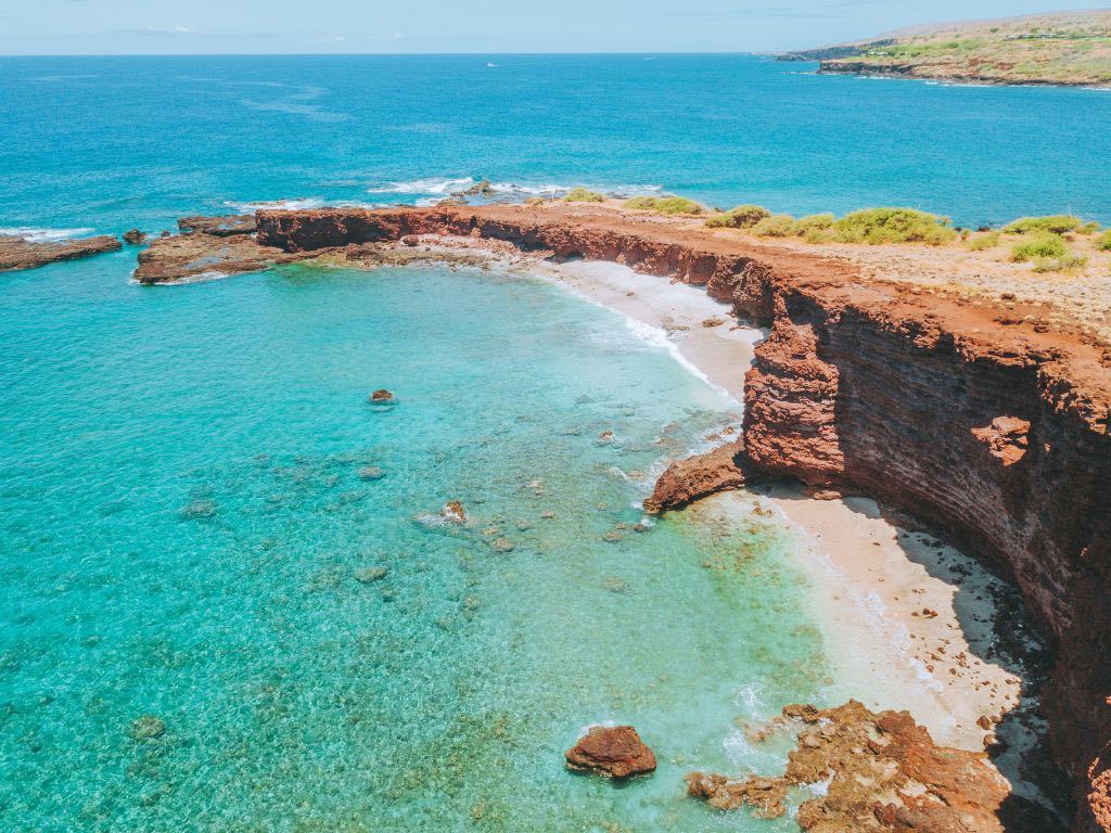 red rock coast of lanai with turquoise sea in background