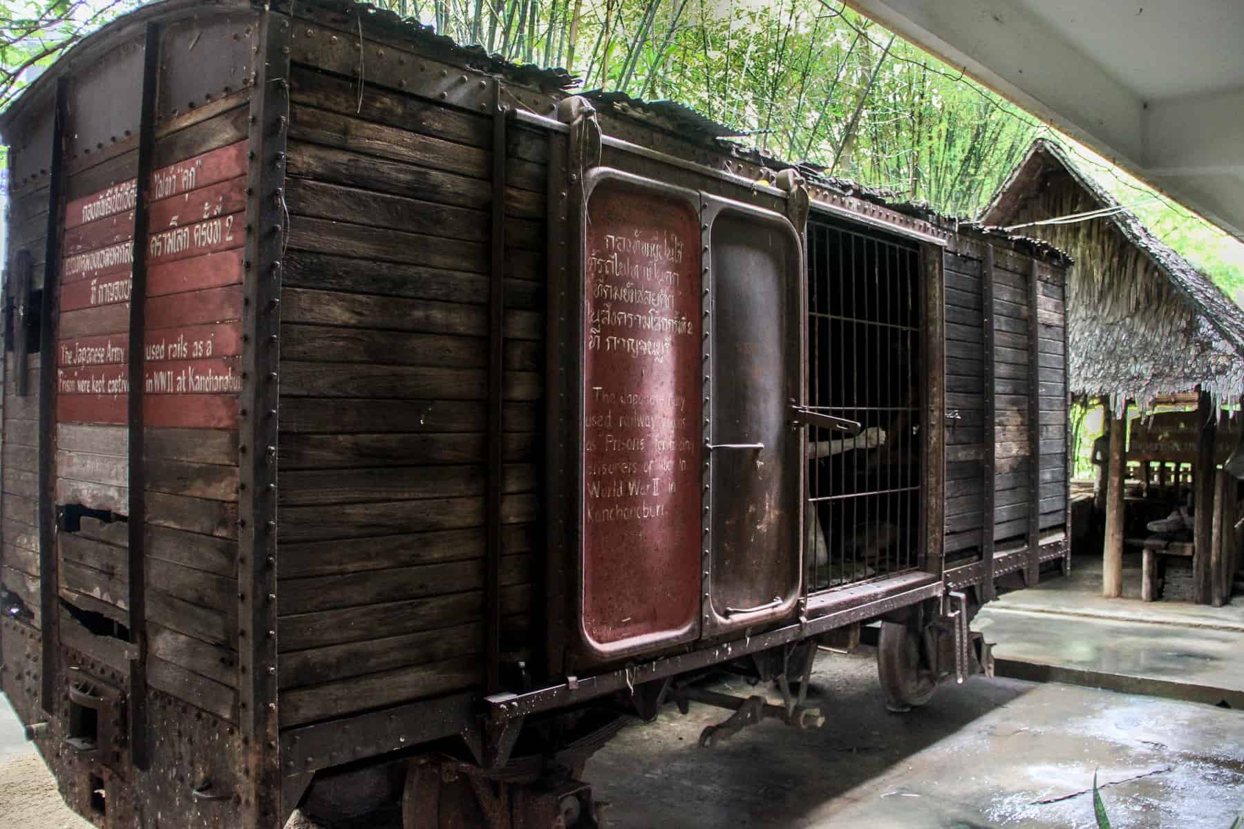 A wooden railway carriage used during the construction of the Death Railway in Thailand, on display in a museum. Wording is inscribed in white on red paint. 