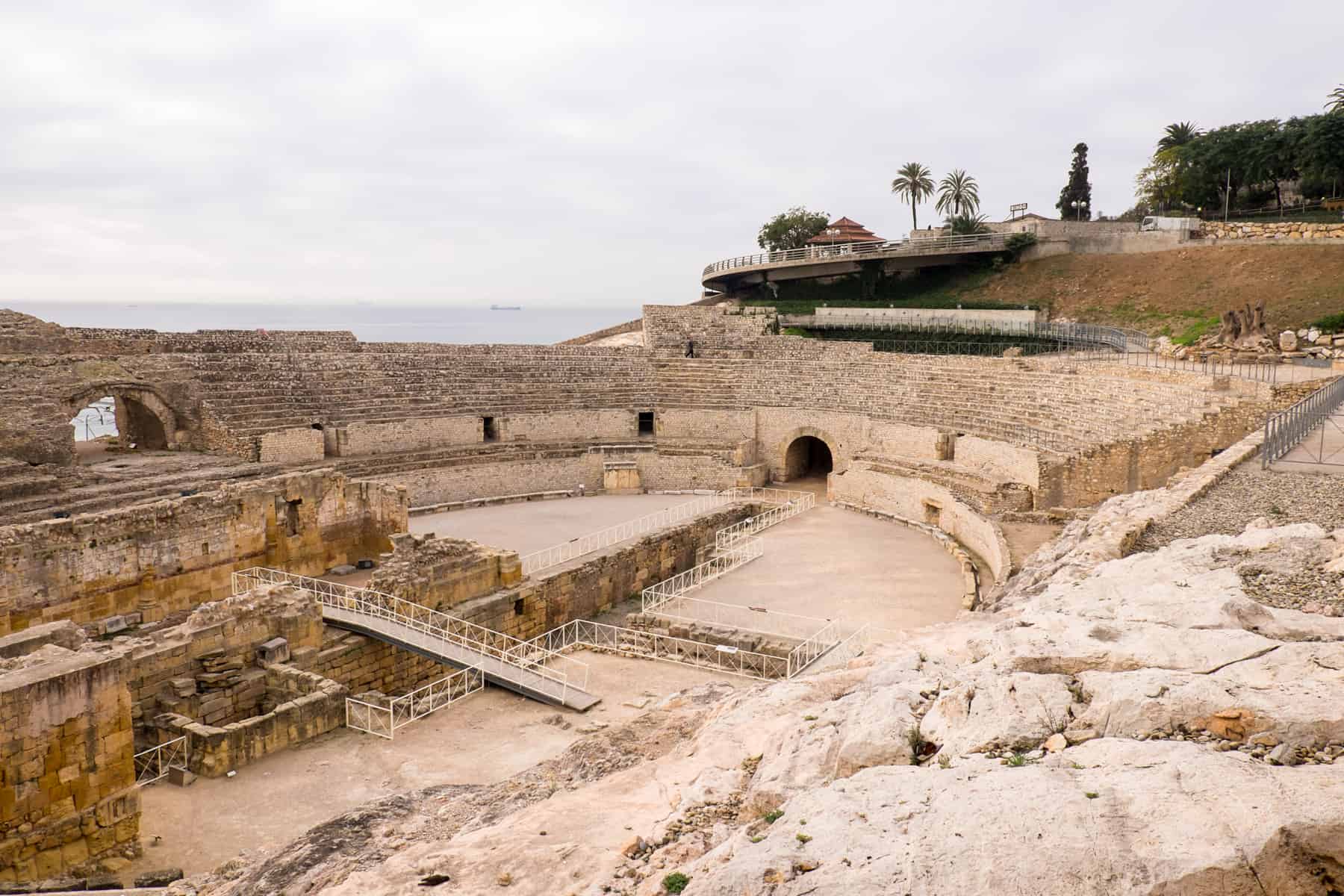The yellowing ruins of the Roman Tarragona Amphitheatre with a view to Mediterranean Sea, Spain