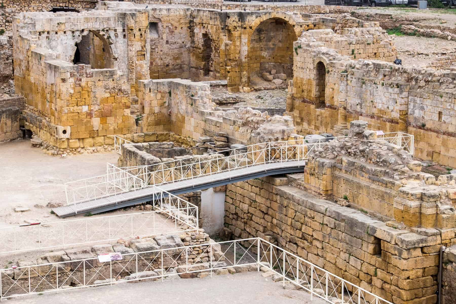 Worn yellow and grey stones of the walls, archways and underground chambers of the Roman Tarragona Amphitheatre 