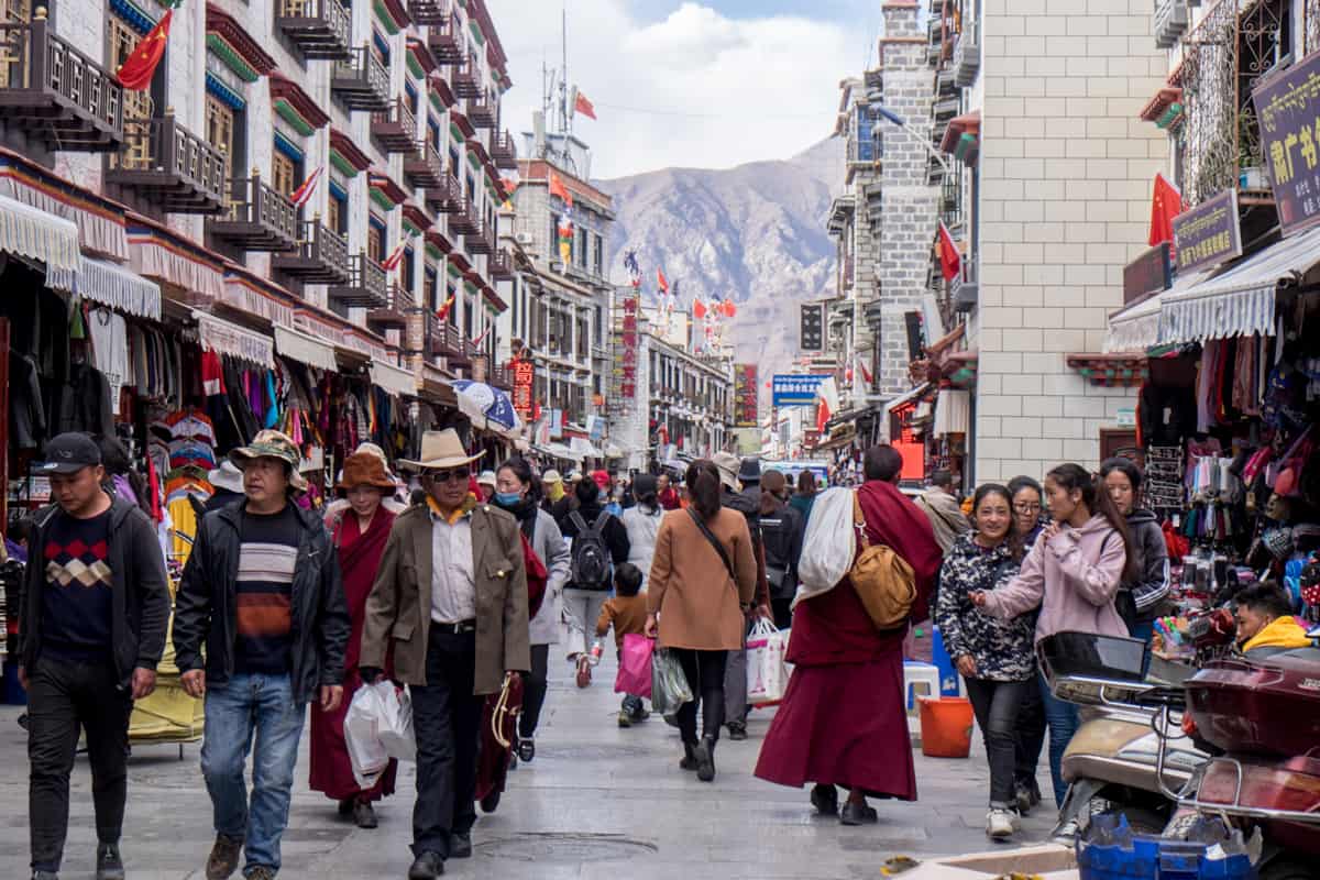 The bustling, busy streets of Lhasa full of a mass of people, Tibet with modern buildings with a mountainous backdrop