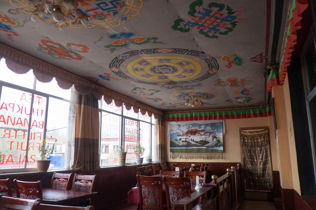 Interior of an authentic Tibetan restaurant in Lhasa, Tibet with wooden panelling and motif embossed materials on the ceiling