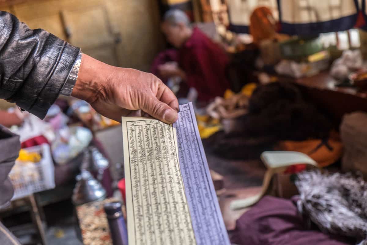 Man holding an unrolled Tibetan Buddhist prayer paper at a nunnery in Lhasa, Tibet