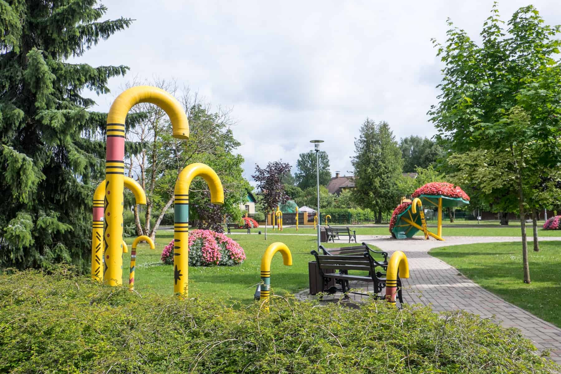 Yellow walking stick structures of varying heights - a symbol of the town - fill a green park in Sigulda, Latvia. 