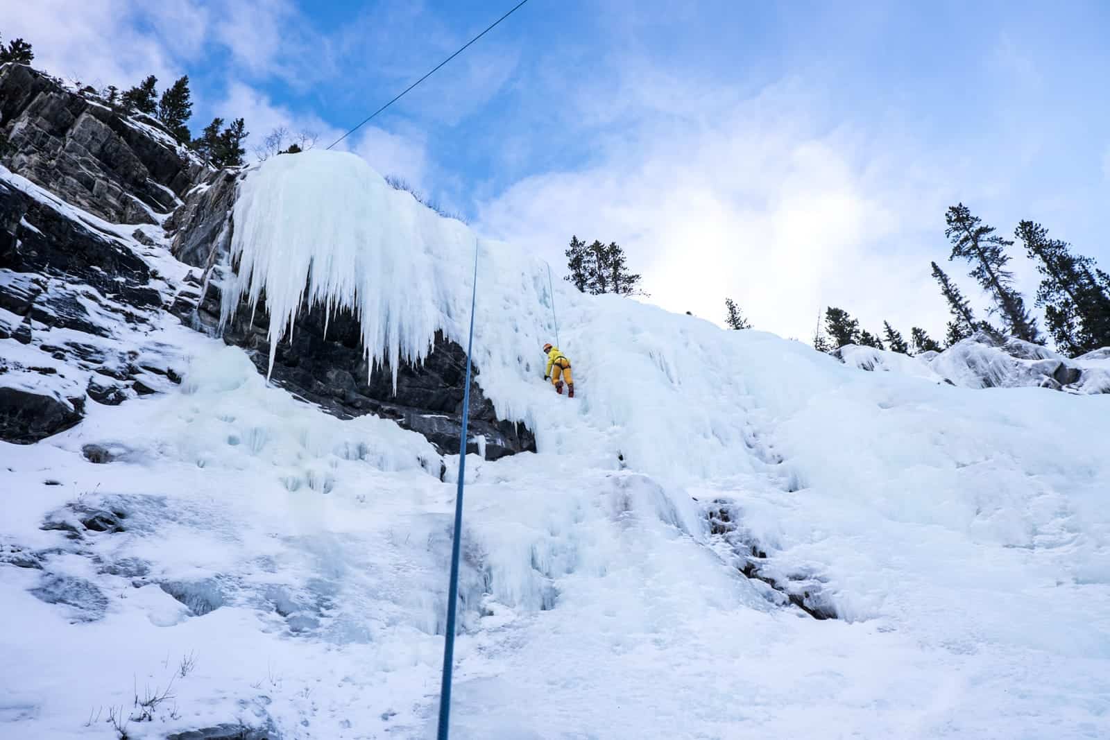 Woman reaches the top of a frozen waterfall in Banff by ice climbing 