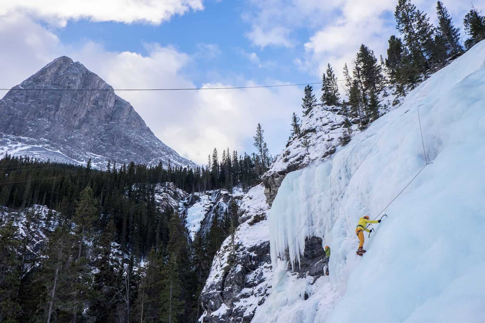 View of mountains and woman ice climbing in Banff during winter 