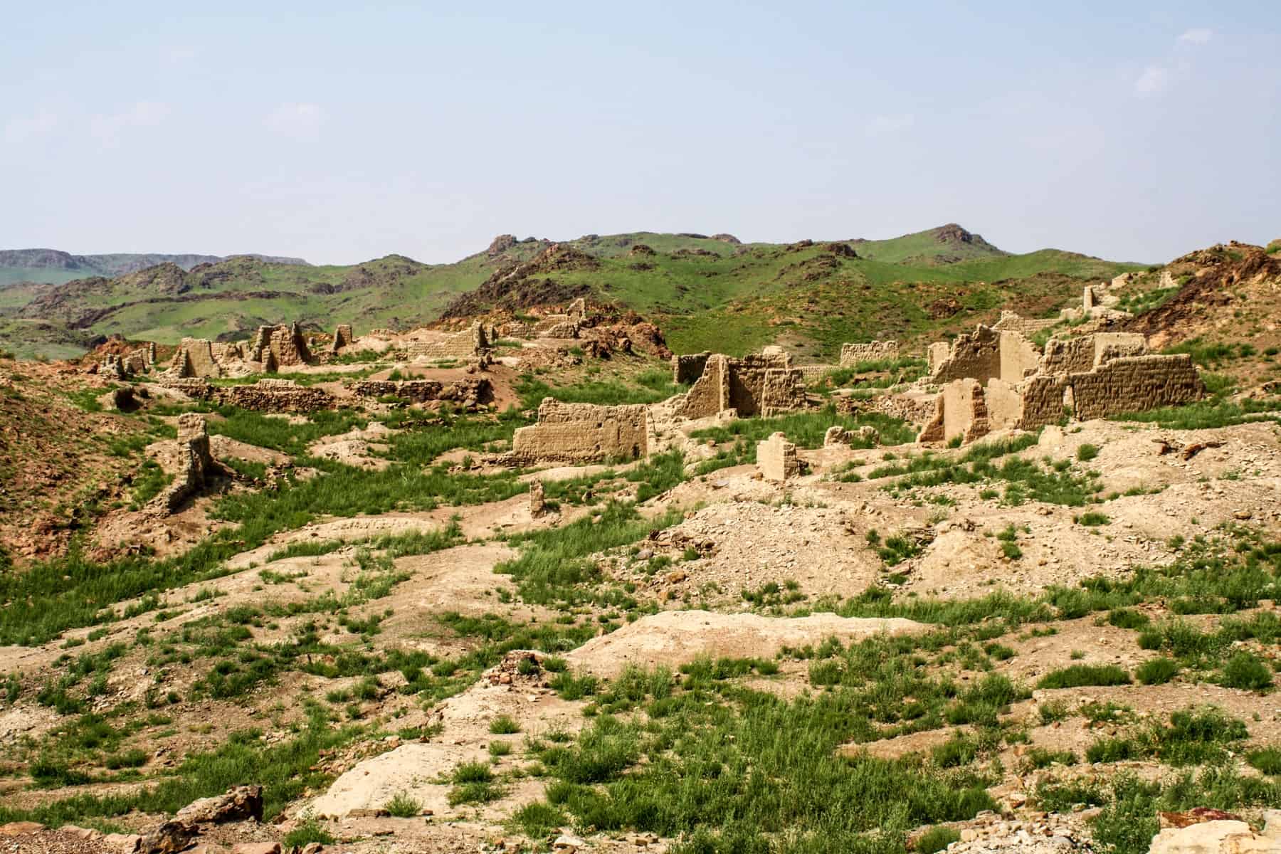 The scattered stone ruins of Ongii Monastery in Mongolia covered by patches of green as nature takes over