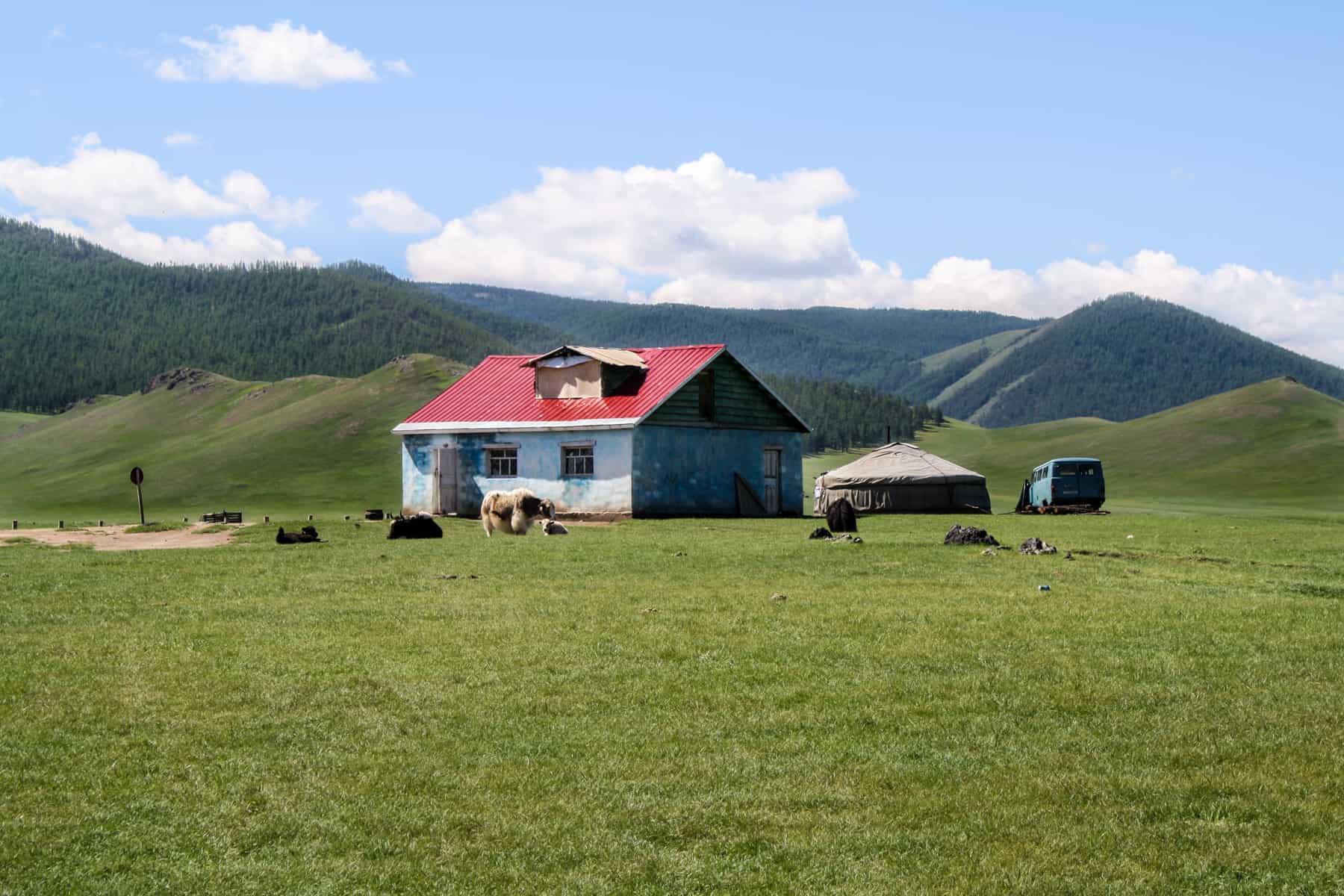 A blue house with a red roof and a white Ger sit isolated in Mongolia's Orkhon Valley
