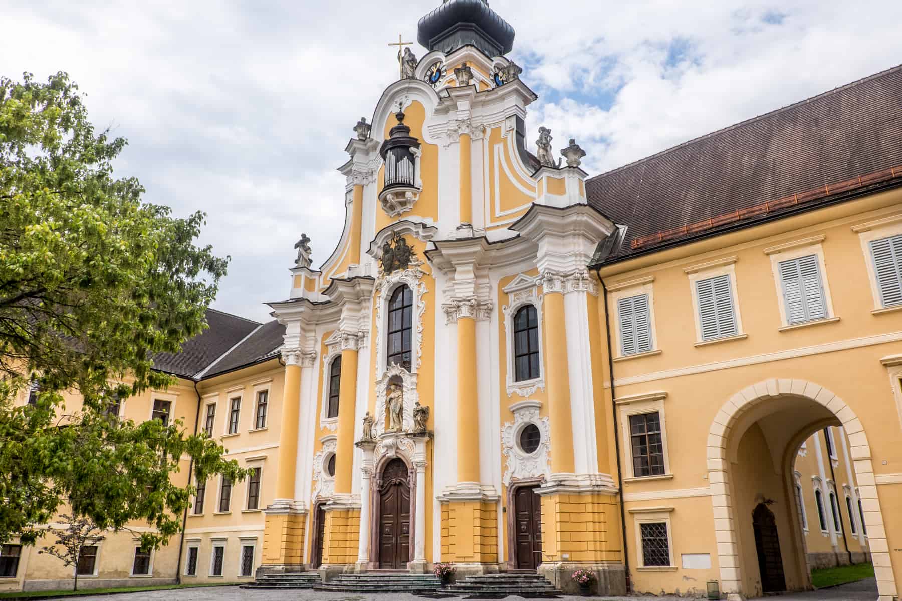The buttery yellow and white columned exterior of the basilica at Rein Abbey - the Oldest Cistercian Monastery in the World Austria