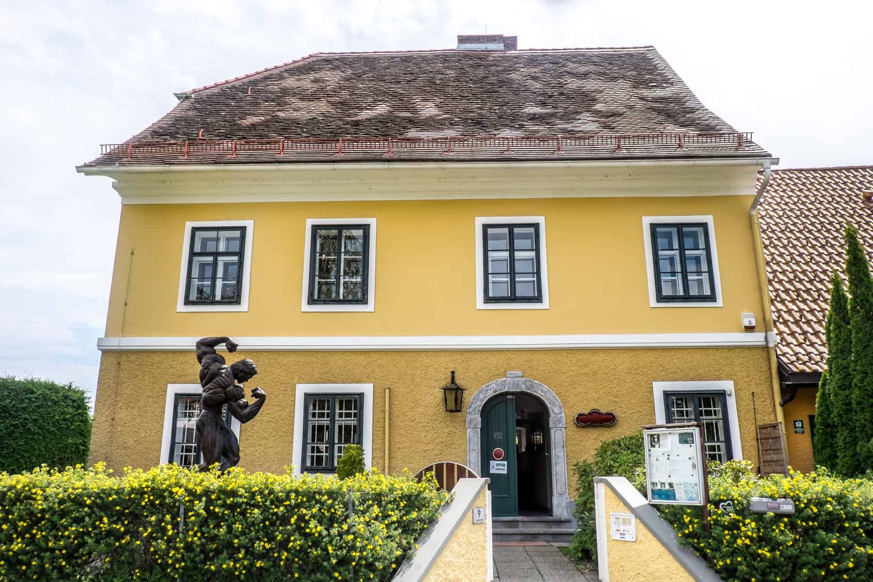 The yellow birth house of Arnold Schwarzenegger in Thal, Austria, marked by a bodybuilding statue outside