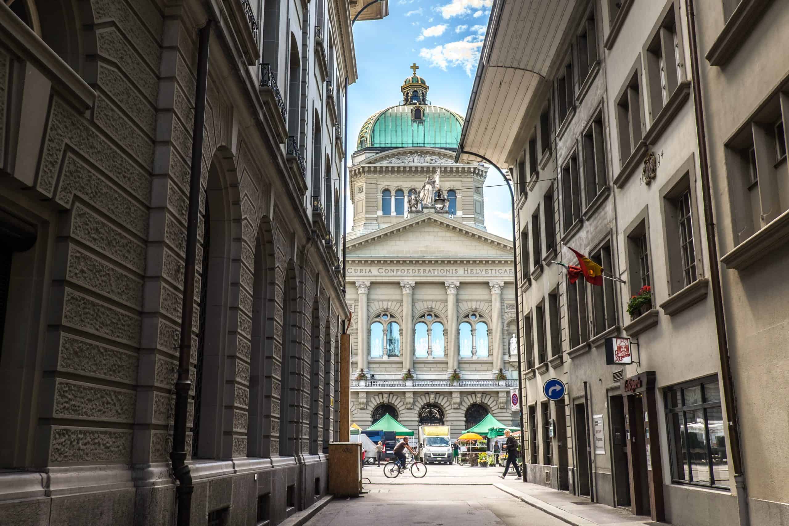 View of turquoise-roofed Swiss Parliament building in Bern, seen from narrow street