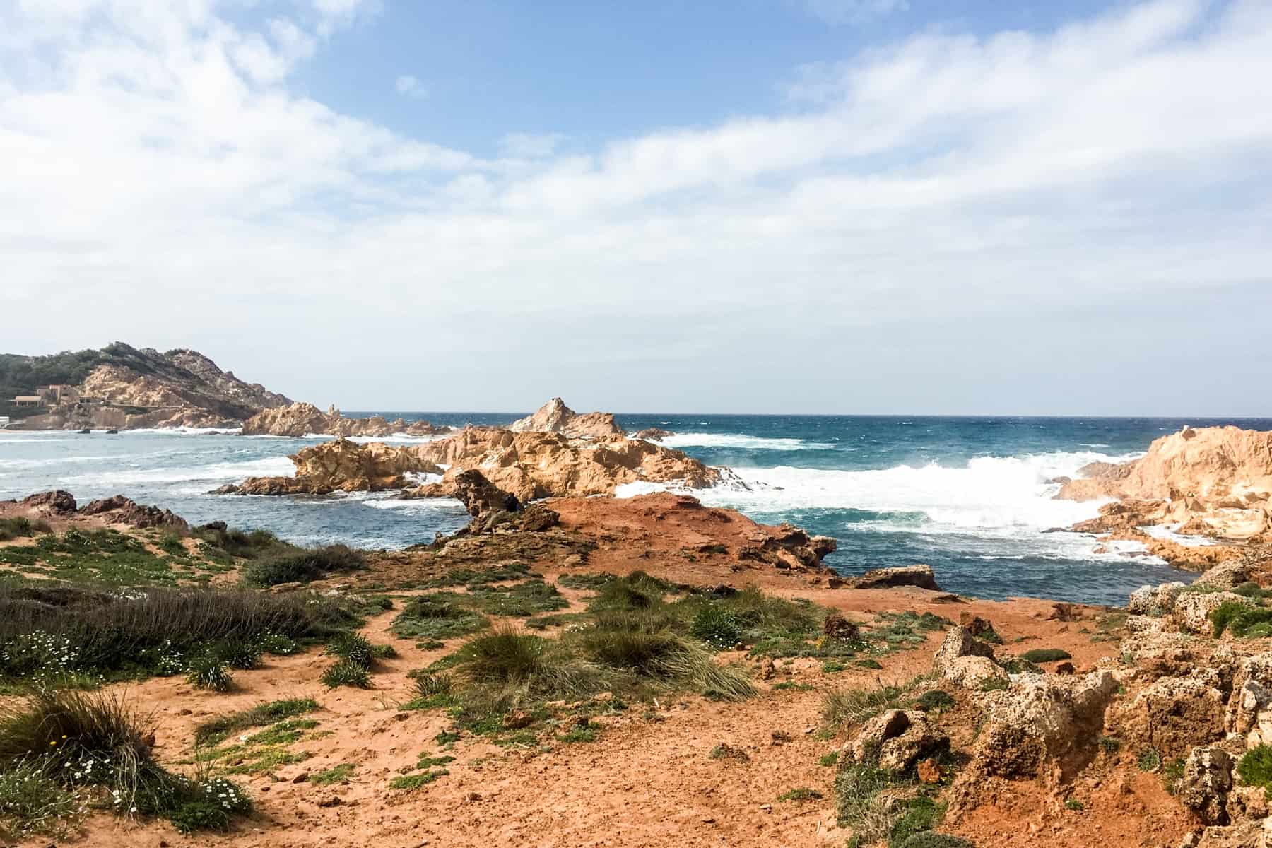 Crashing waves break on the golden rocky coastline of Menorca, Spain. 