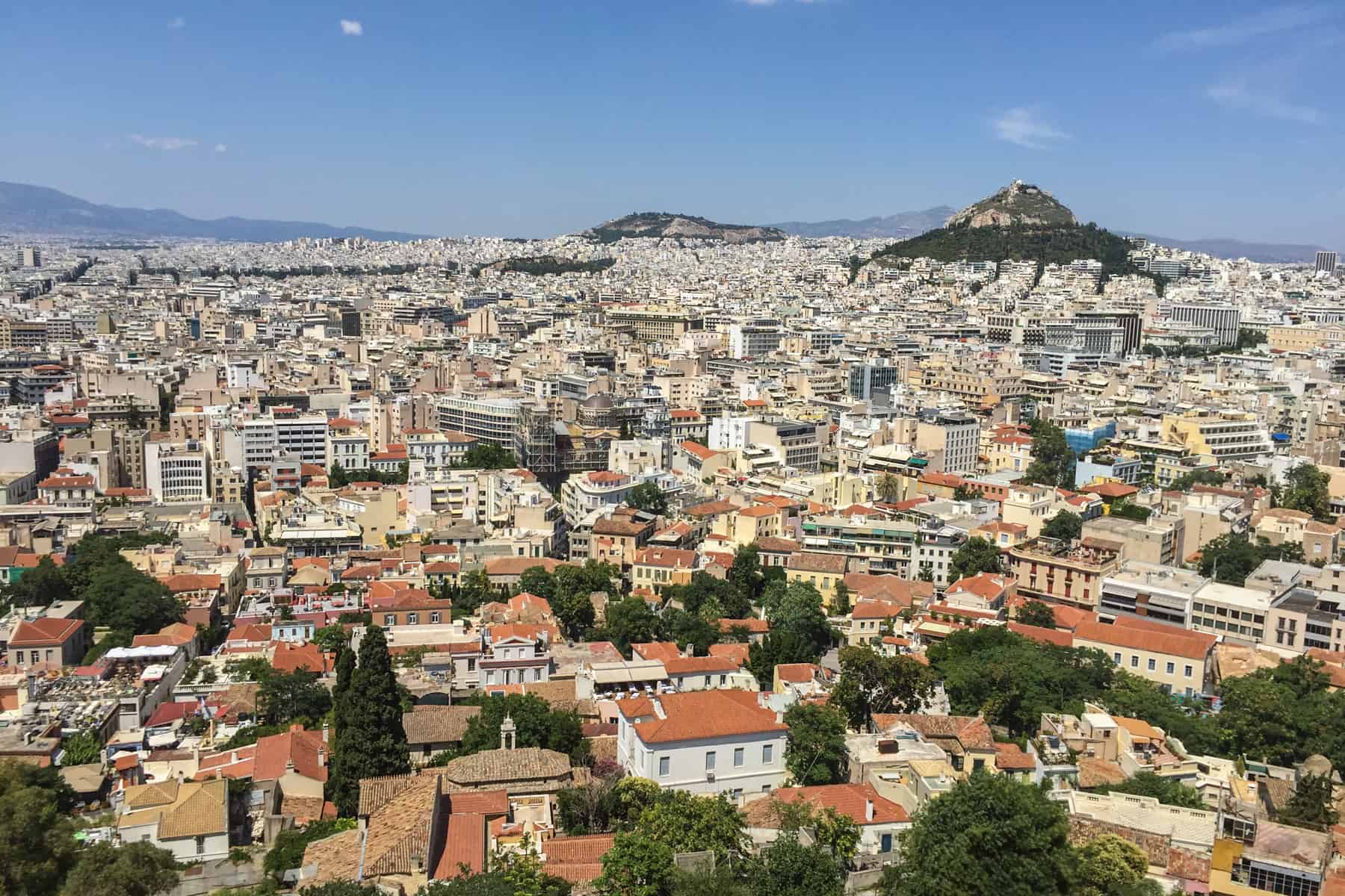 Compacted Athens city structures as seen from elevation, with two small green hills poking through in the background.