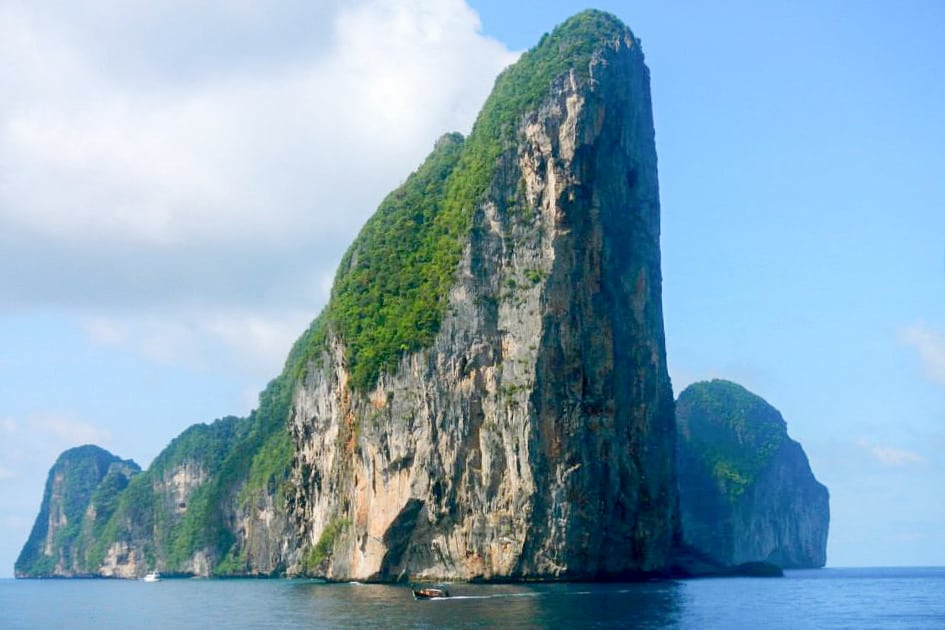 The grass covered, tall, rocky cliff face of Koh Phi Phi Leh island in Thailand where The Beach was filmed. 