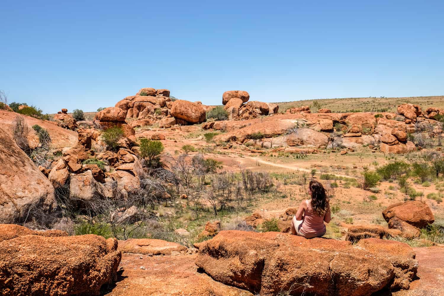 A woman sits within the formations of the Devil's Marble in the Northern Territory, Australia. 