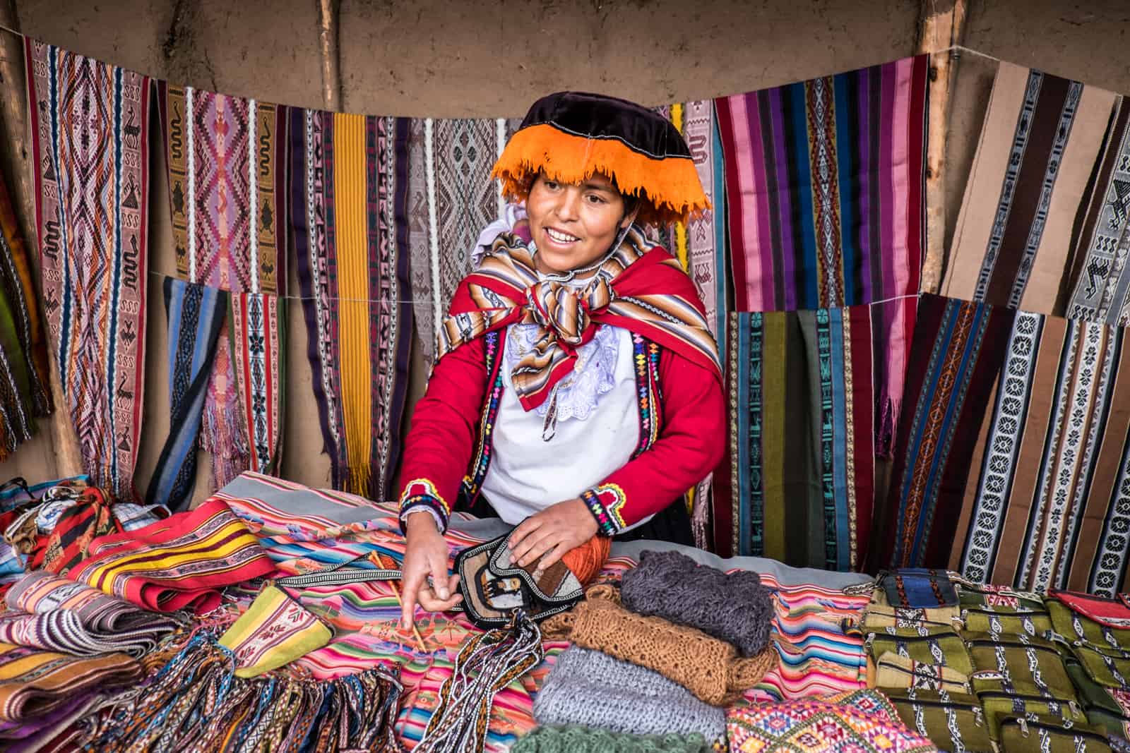 A Peruvian woman in traditional dress shows the handmade souvenirs the Ccaccaccollo Women’s Weaving Co-op in the Sacred Valley.