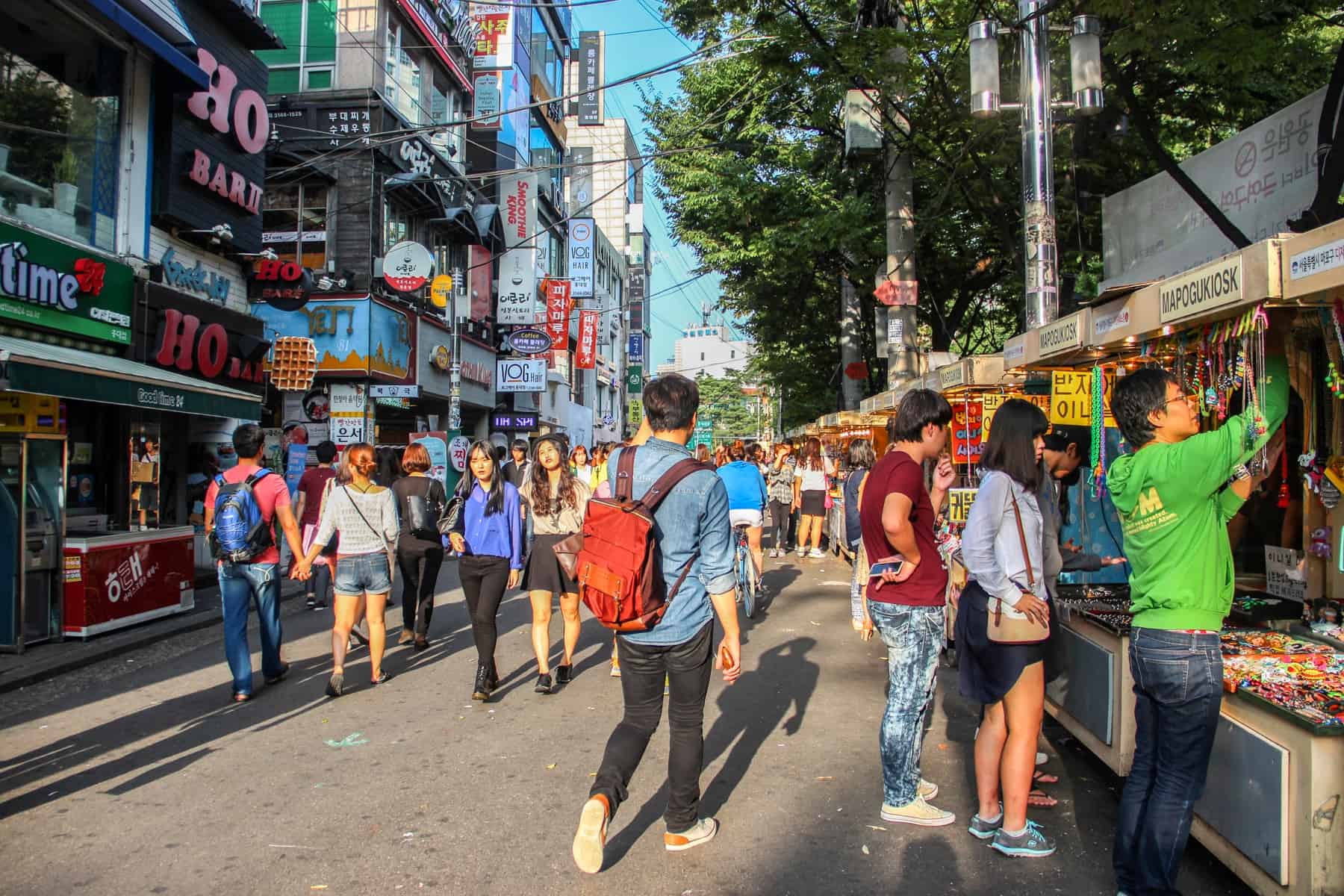 Locals on a busy street in Seoul, South Korea lined with tall buildings and markets stalls. 