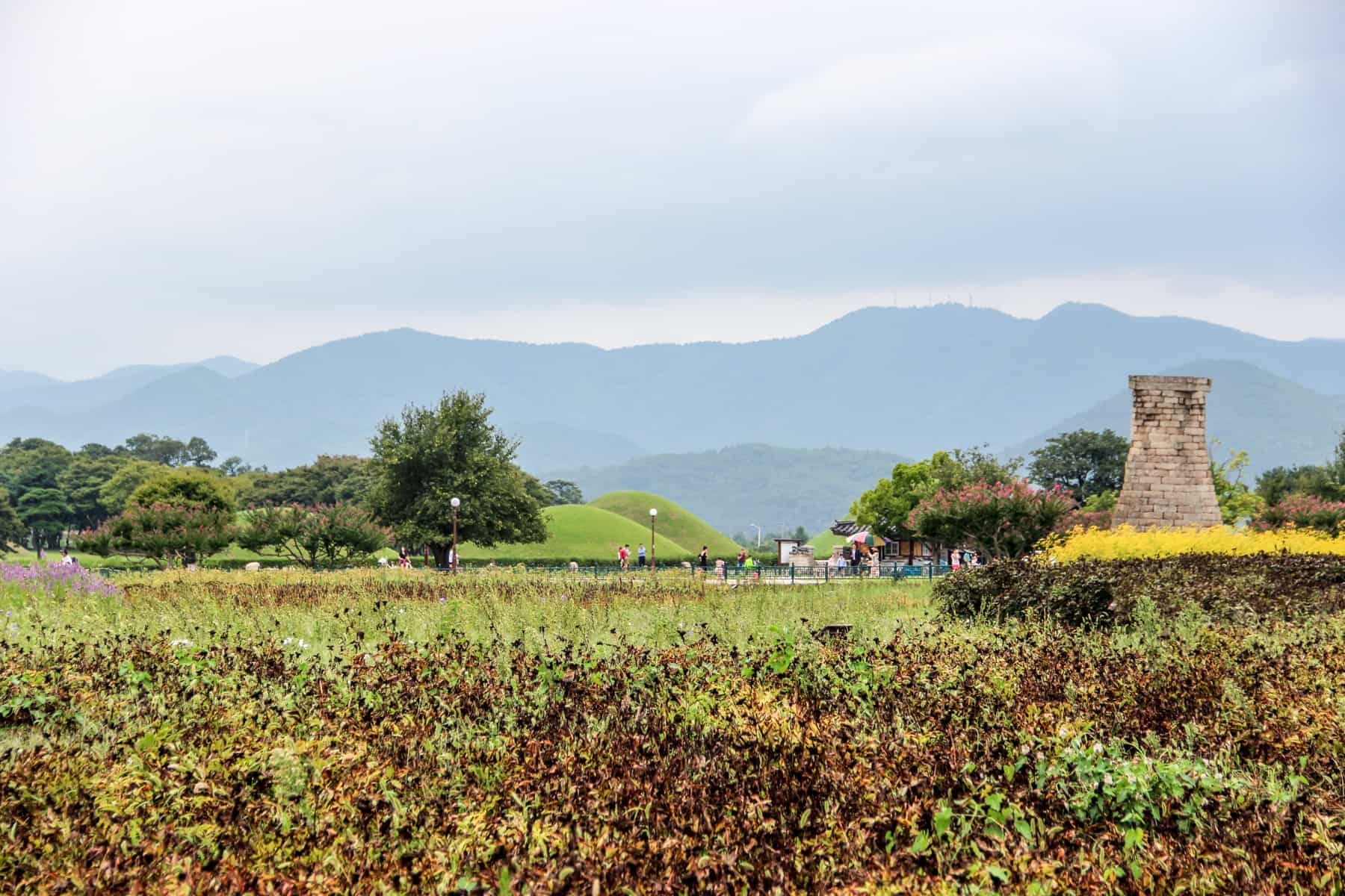 The grassy royal burial mounds in Gyeongju South Korea to a backdrop of mountains.