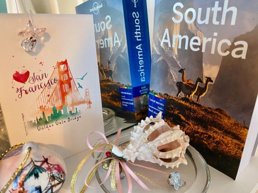 shelf with travel souvenirs including shell, postcard and travel book