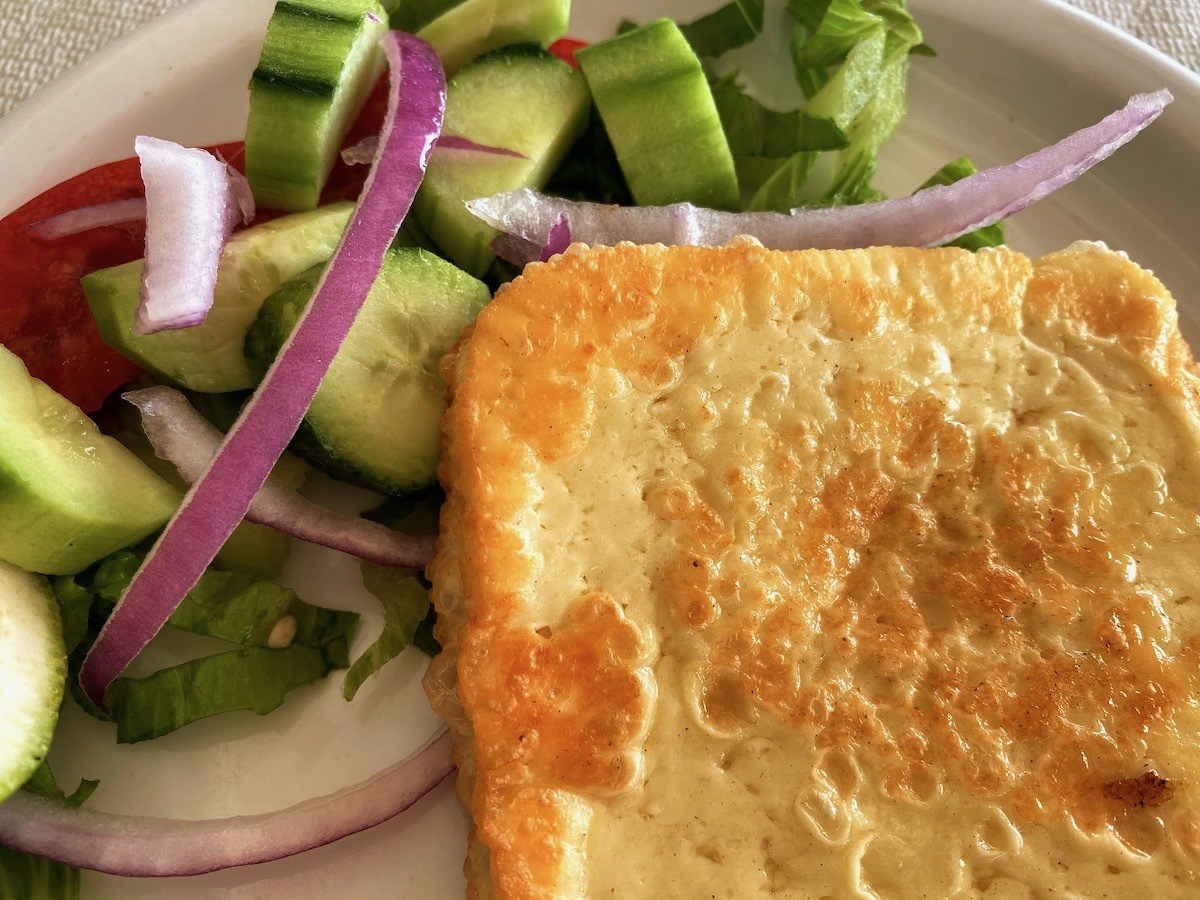 Square of fried Greek cheese with salad