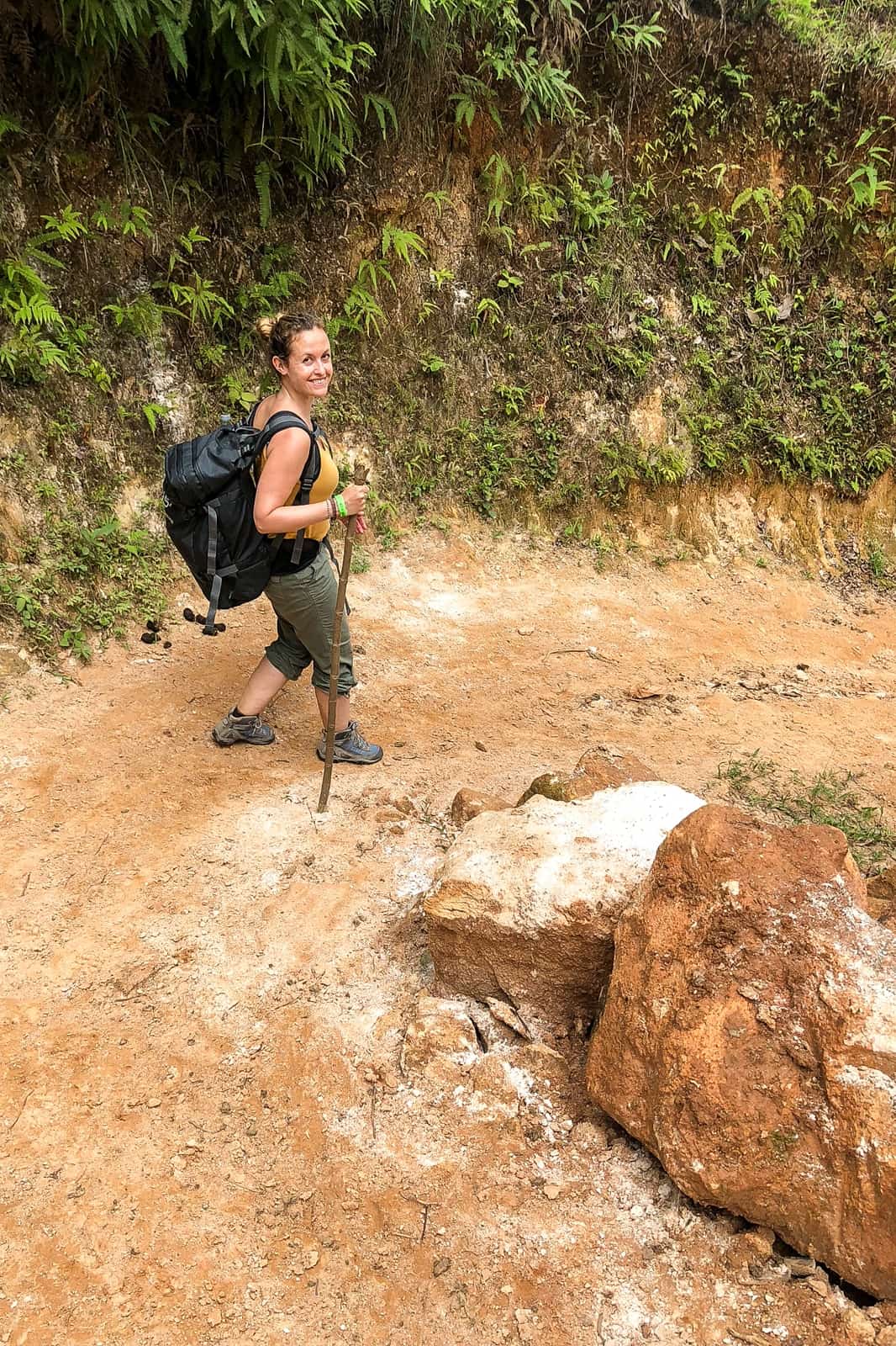Traveller carrying a small black backpack and walking stick for the Lost City Trek.