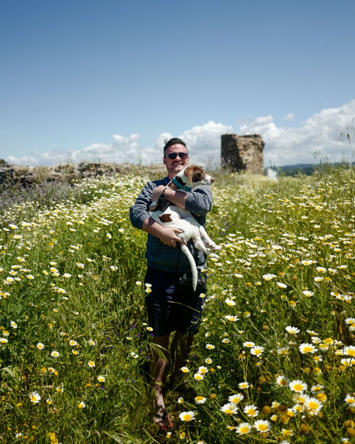 Dan with a dog surrounded by wild flowers
